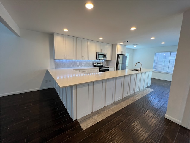 kitchen featuring sink, white cabinetry, kitchen peninsula, decorative backsplash, and appliances with stainless steel finishes