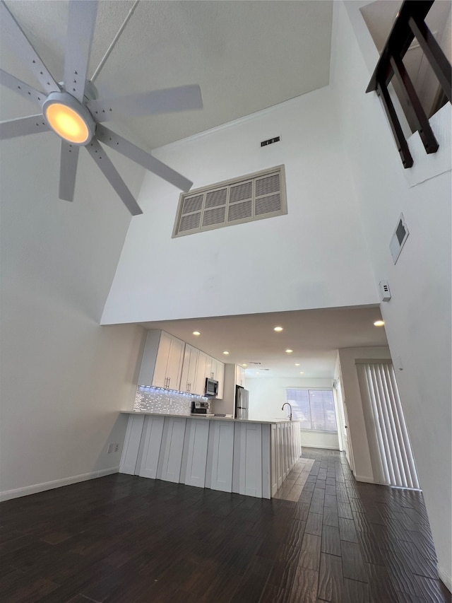 interior space with ceiling fan, hardwood / wood-style flooring, and a high ceiling