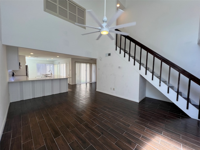 unfurnished living room featuring a high ceiling, ceiling fan, dark hardwood / wood-style floors, and sink