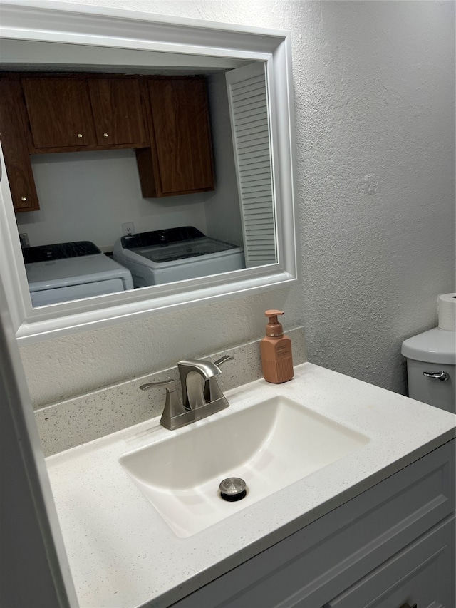 bathroom featuring washer and clothes dryer, vanity, and toilet