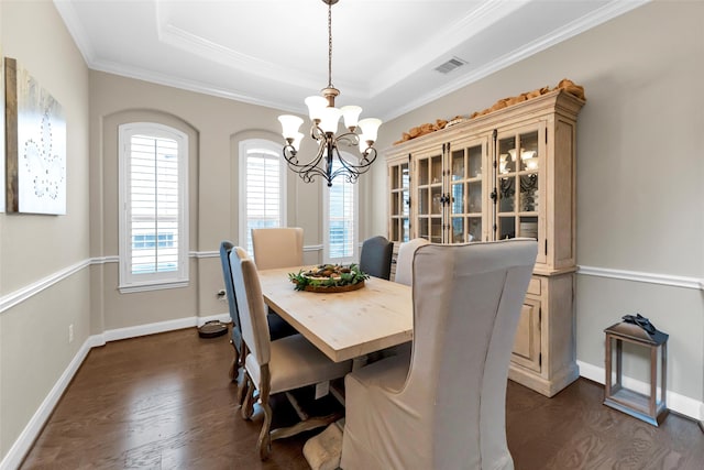 dining room featuring a tray ceiling, crown molding, dark hardwood / wood-style flooring, and an inviting chandelier