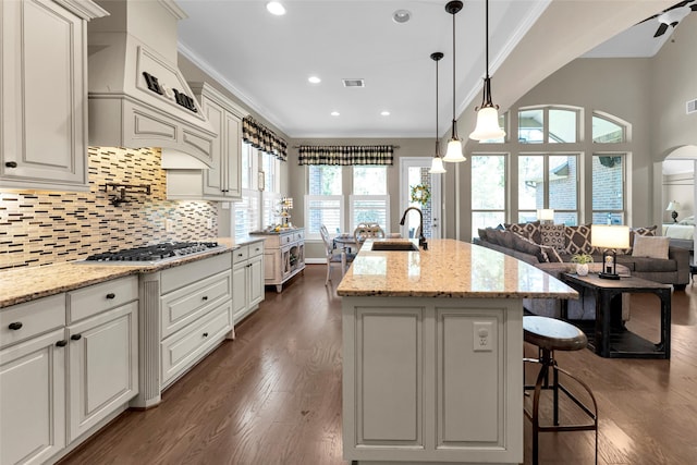 kitchen featuring dark hardwood / wood-style flooring, sink, decorative light fixtures, stainless steel gas stovetop, and an island with sink