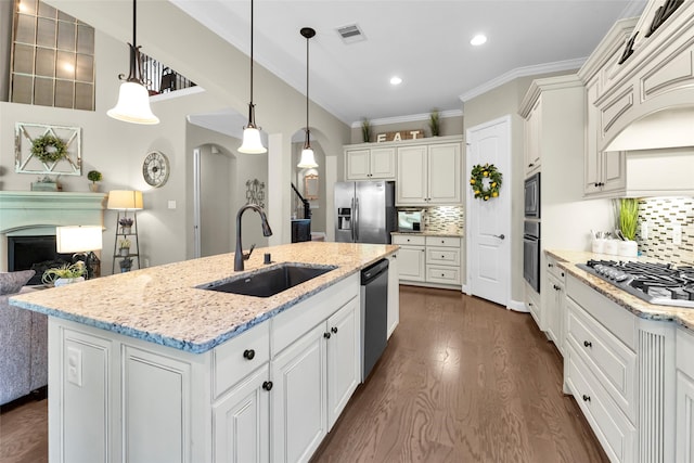 kitchen with sink, an island with sink, decorative light fixtures, decorative backsplash, and appliances with stainless steel finishes