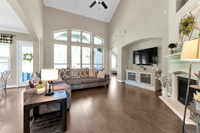 living room featuring ceiling fan, dark hardwood / wood-style flooring, high vaulted ceiling, and ornamental molding