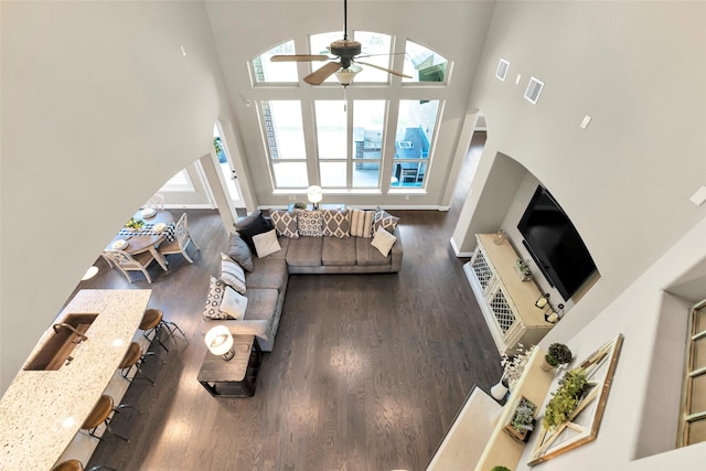 living room featuring dark hardwood / wood-style flooring, a towering ceiling, and ceiling fan