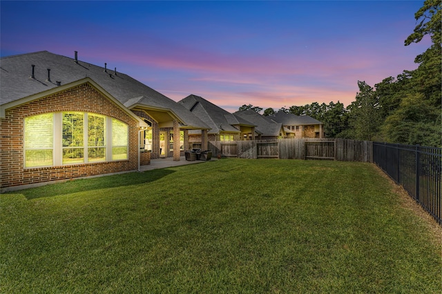 back house at dusk with a yard and a patio