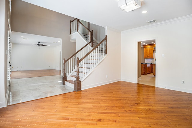 stairs with wood-type flooring, ceiling fan, and crown molding