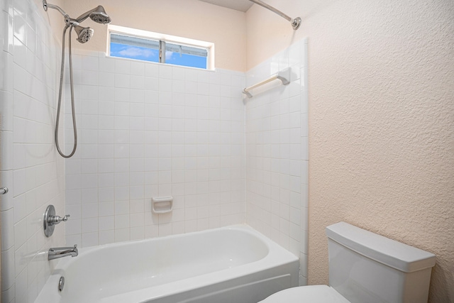 bathroom featuring toilet and tiled shower / bath