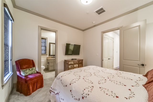 bedroom featuring crown molding, light carpet, and ensuite bath