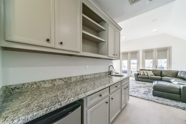 kitchen featuring light stone countertops, light colored carpet, lofted ceiling, and sink