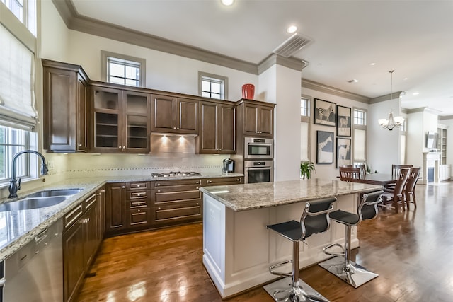 kitchen with dark brown cabinetry, stainless steel appliances, dark wood-type flooring, sink, and a center island