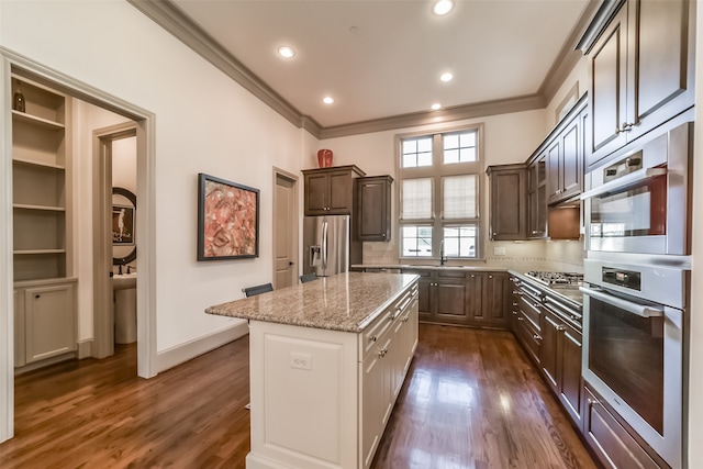 kitchen featuring ornamental molding, stainless steel appliances, sink, a center island, and dark hardwood / wood-style floors