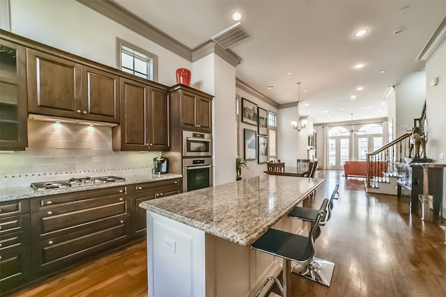 kitchen featuring a kitchen breakfast bar, dark brown cabinetry, a center island, and stainless steel appliances