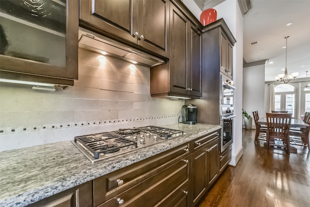 kitchen featuring backsplash, dark brown cabinets, stainless steel appliances, decorative light fixtures, and dark hardwood / wood-style floors