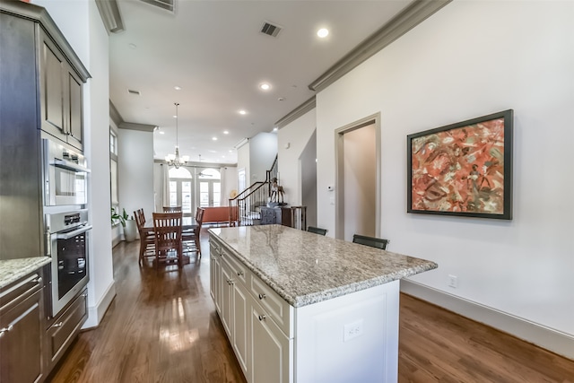 kitchen with a center island, an inviting chandelier, ornamental molding, decorative light fixtures, and dark hardwood / wood-style flooring