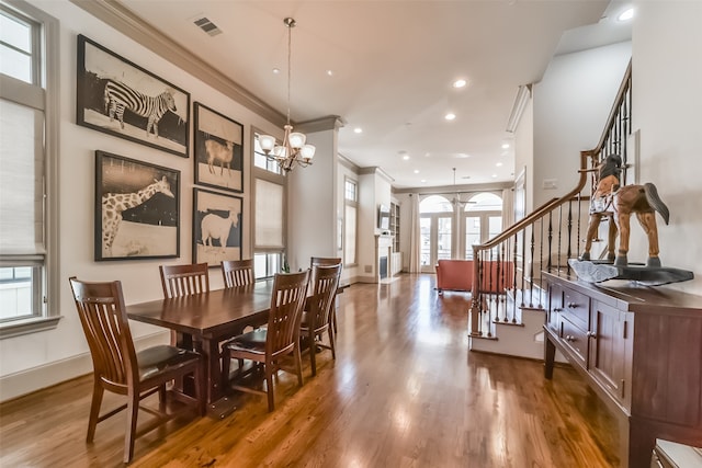 dining area featuring hardwood / wood-style floors, crown molding, and a notable chandelier