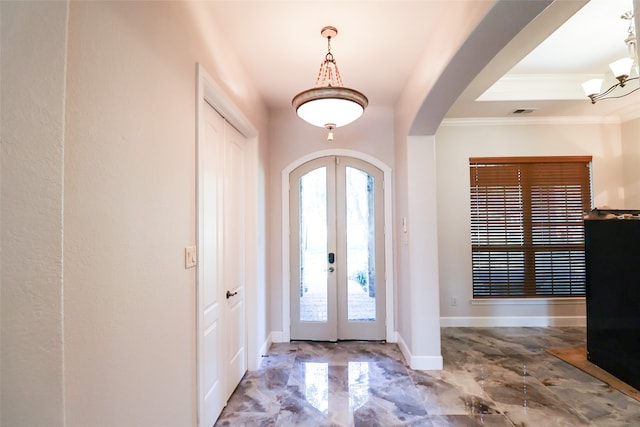 foyer entrance with ornamental molding, a notable chandelier, and french doors