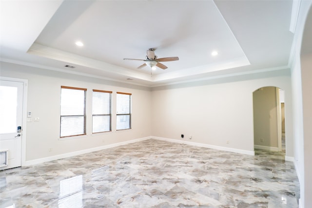 empty room with ornamental molding, a tray ceiling, and ceiling fan