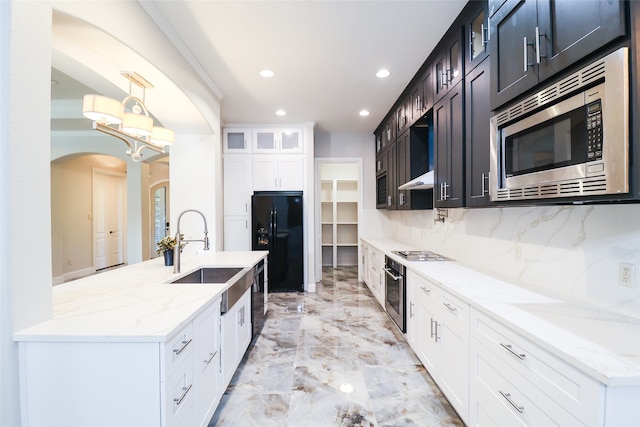 kitchen featuring sink, hanging light fixtures, backsplash, appliances with stainless steel finishes, and light stone countertops