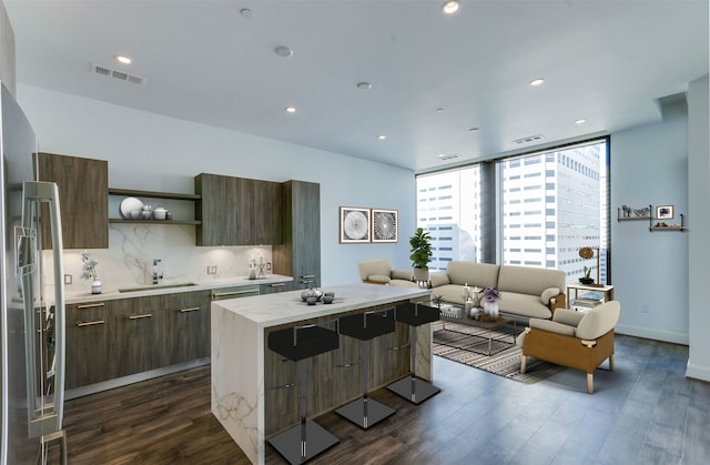 kitchen with decorative backsplash, a kitchen island, a breakfast bar area, dark hardwood / wood-style floors, and sink