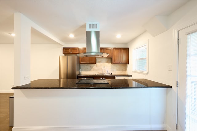 kitchen with stainless steel fridge, kitchen peninsula, decorative backsplash, and a wealth of natural light