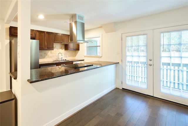 kitchen with stainless steel fridge, dark wood-type flooring, kitchen peninsula, island exhaust hood, and sink