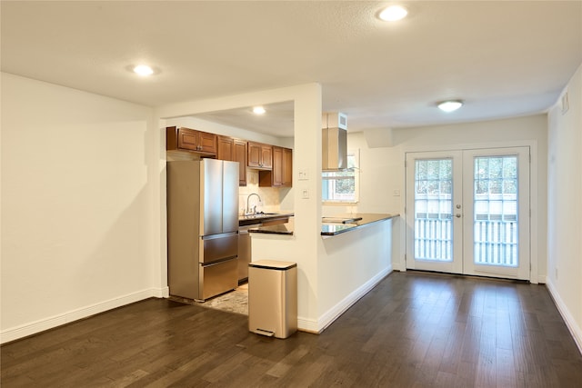 kitchen with stovetop, kitchen peninsula, dark hardwood / wood-style flooring, french doors, and stainless steel fridge