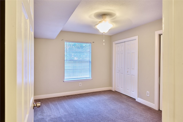 unfurnished bedroom with a closet, ceiling fan, carpet floors, and a textured ceiling