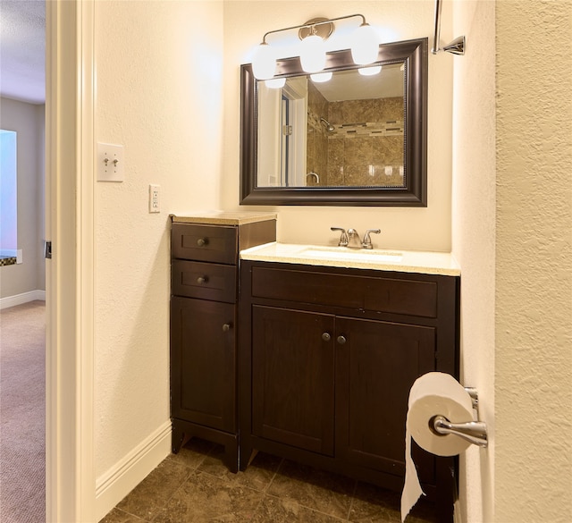 bathroom featuring vanity, tile patterned flooring, a textured ceiling, and tiled shower