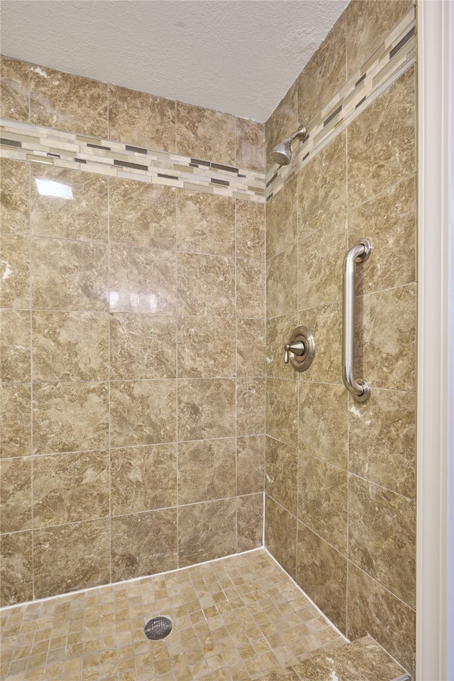 bathroom featuring a textured ceiling and tiled shower