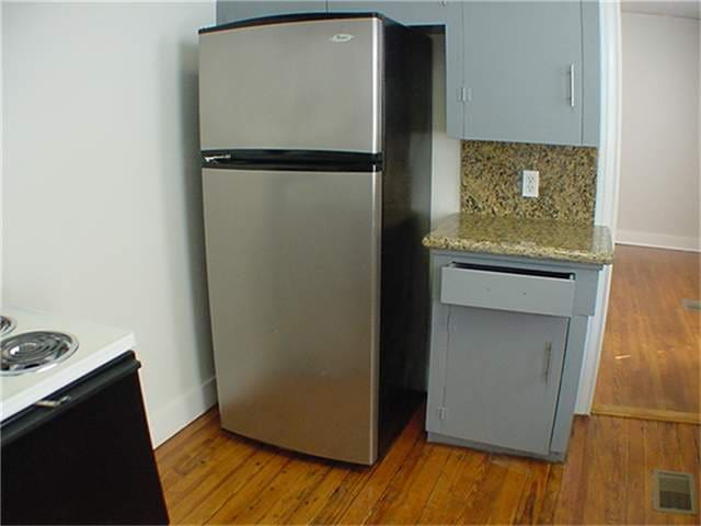 kitchen with stainless steel refrigerator, backsplash, hardwood / wood-style floors, and range with electric cooktop