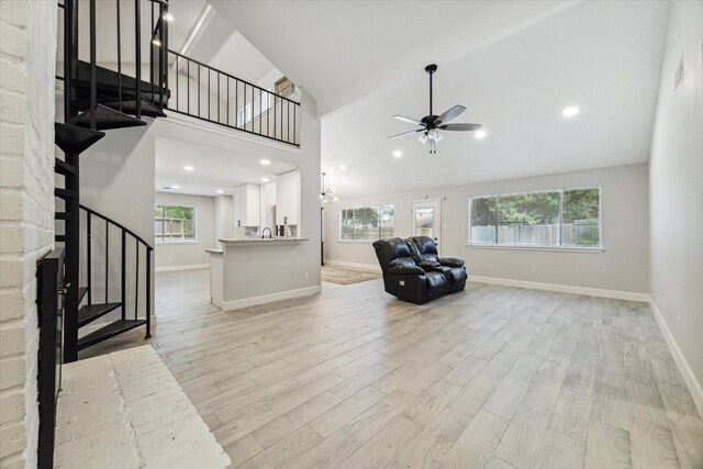 unfurnished living room with ceiling fan, light hardwood / wood-style flooring, high vaulted ceiling, and a healthy amount of sunlight