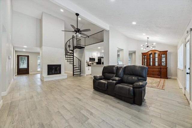 living room featuring beam ceiling, high vaulted ceiling, a fireplace, ceiling fan with notable chandelier, and light hardwood / wood-style floors