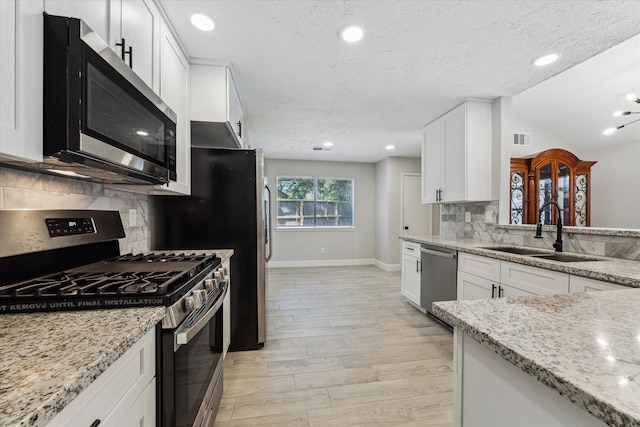 16007 Soma Dr, Houston, TX 77083 - kitchen featuring a sink, stainless steel appliances, light stone counters, white cabinetry, and baseboards
