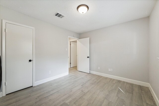 unfurnished bedroom featuring a textured ceiling and light hardwood / wood-style floors