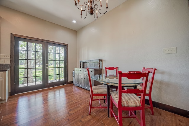 dining space with hardwood / wood-style floors, vaulted ceiling, and an inviting chandelier