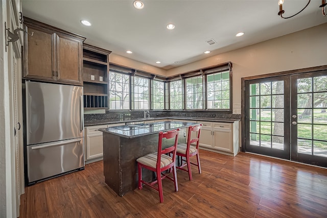 kitchen with dark hardwood / wood-style floors, a breakfast bar area, a kitchen island, french doors, and stainless steel fridge