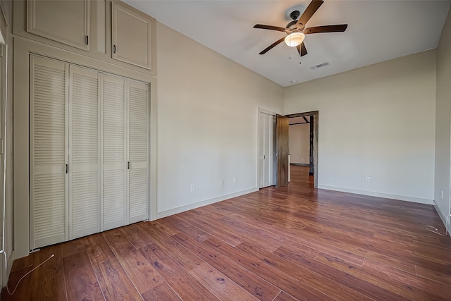 unfurnished bedroom featuring wood-type flooring, ceiling fan, and a barn door