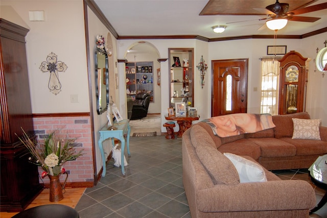 living area featuring arched walkways, ceiling fan, crown molding, and dark tile patterned floors