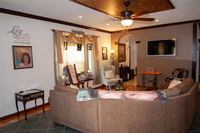 living room with dark tile patterned flooring, ceiling fan, and crown molding