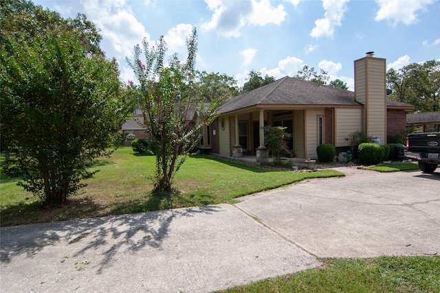 view of front of property with a chimney, a front lawn, and concrete driveway