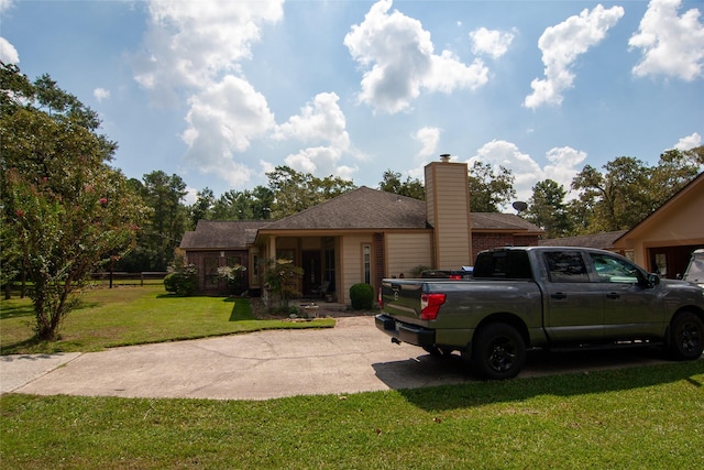 view of front facade featuring a front lawn, driveway, and a chimney