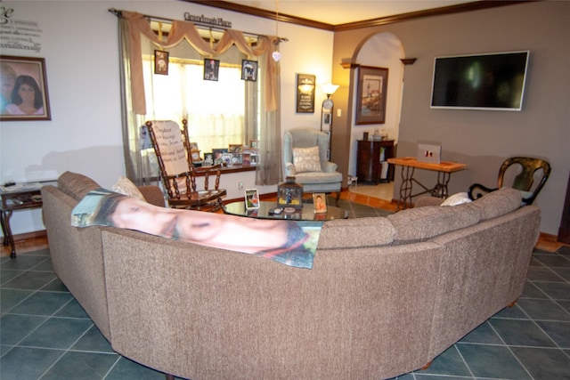 living area featuring baseboards, arched walkways, dark tile patterned floors, and ornamental molding