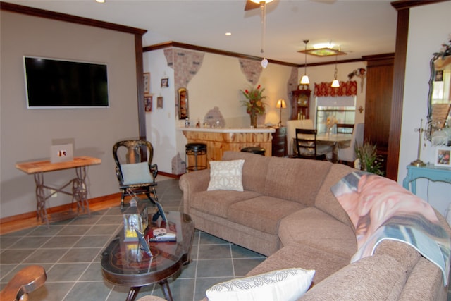 living room featuring ceiling fan, a fireplace, ornamental molding, and dark tile patterned flooring