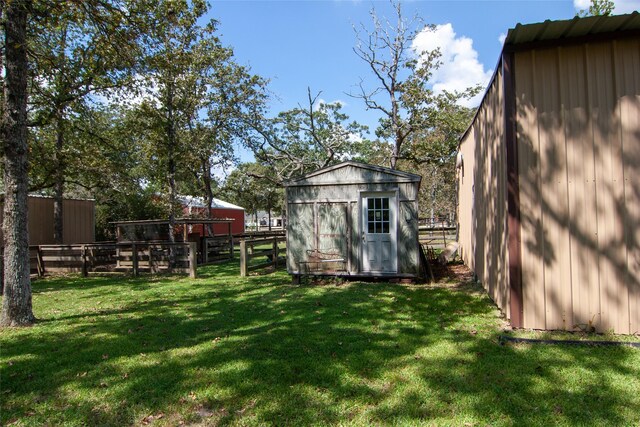 view of yard featuring an outdoor structure, fence, and a storage shed