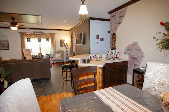 dining space with ceiling fan, ornamental molding, dark wood-type flooring, and sink