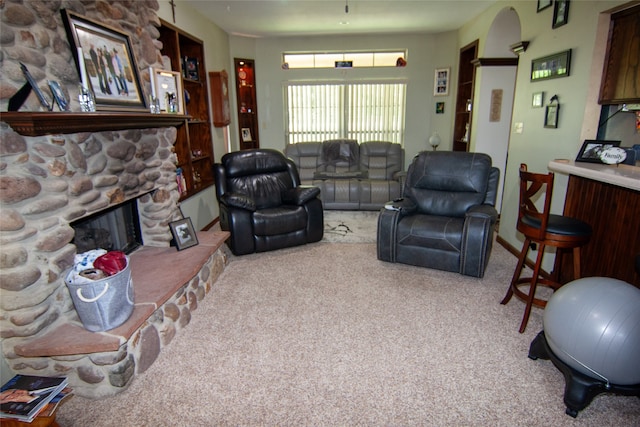 carpeted living room with a stone fireplace