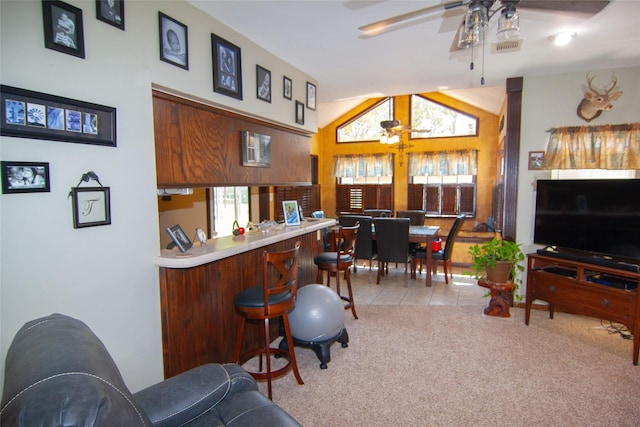 kitchen featuring a ceiling fan, a breakfast bar area, open floor plan, tile patterned flooring, and carpet