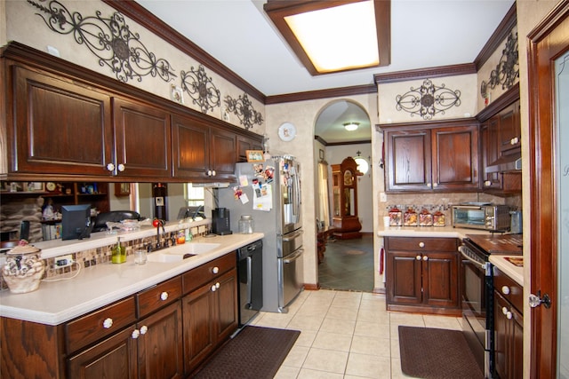 kitchen featuring light countertops, crown molding, light tile patterned floors, arched walkways, and appliances with stainless steel finishes
