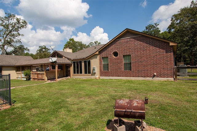 back of property with brick siding, fence, a chimney, and a yard